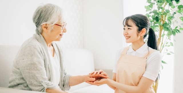利用者様のご自宅を訪問した看護師が手を取り合っている様子