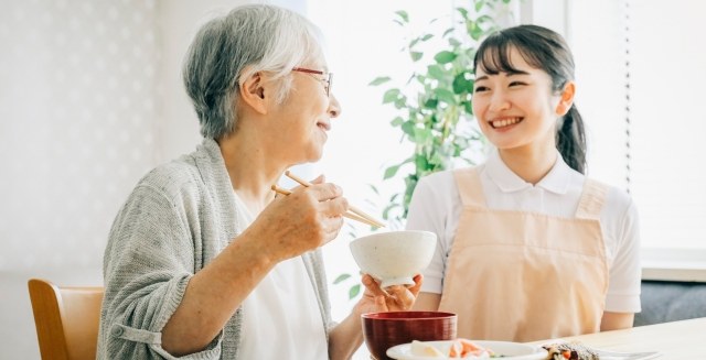 利用者様とスタッフが食卓を囲んで談笑している様子