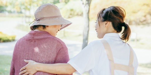 屋外を散歩する利用者様に寄り添うスタッフ